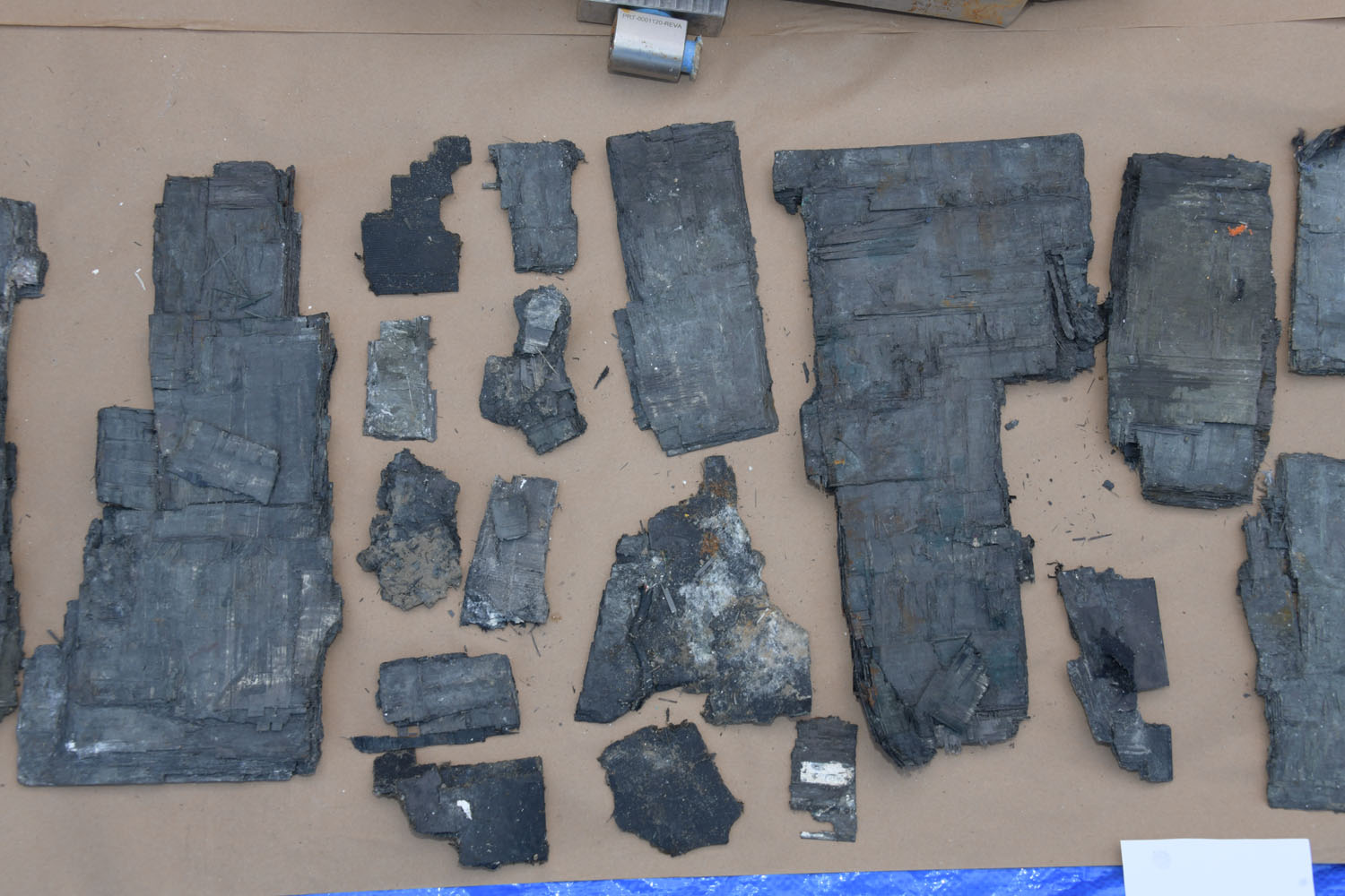 Recovered carbon-fiber hull fragments arranged on a surface for examination
